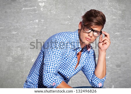 Fashion young man holding his fashionable glasses on gray background