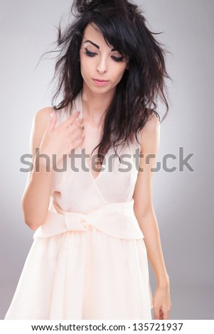 sexy young fashion woman looking down while she throws her hair back. on gray background