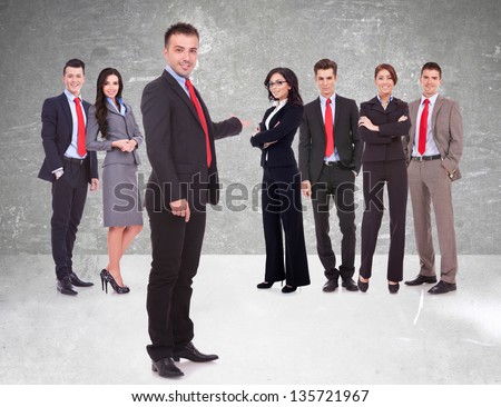 Successful happy business team being presented by a young leader, on gray background. young business man welcoming you to his business team