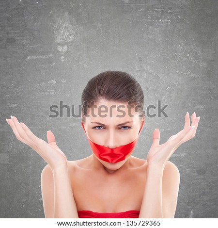 angry woman with mouth covered with a red ribbon over gray background