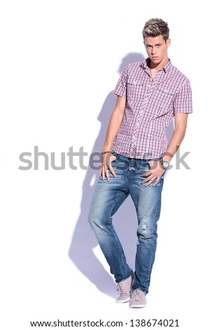 casual young man holding his thumbs in his pockets and looking at the camera. on white background with hard shadow
