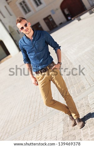 diagona view of a casual young man posing with a hand in his pocket and looking at the camera