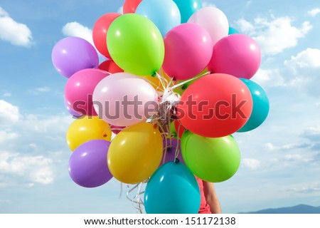 casual young man holding balloons in front of him outdoor