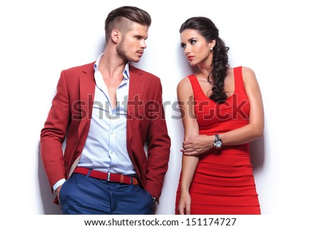 casual fashion man and woman looking at each other while leaning against white wall
