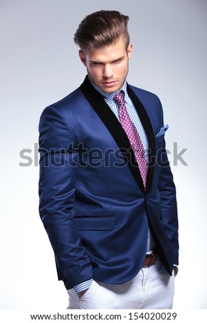 closeup of a young business man looking away from the camera while holding both hands in pockets. on a white background