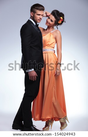 full length photo of a young fashion couple with woman smiling and man looking away from the camera. on gray background