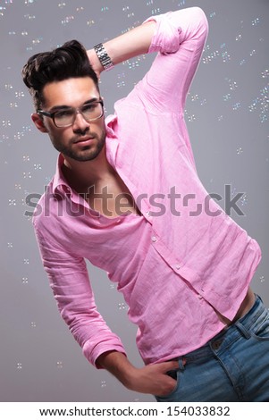 young fashion man posing with a hand at the back of his head and the other in his pocket while being surrounded by bubbles. on a white background