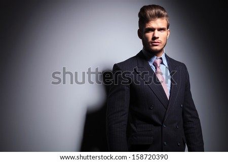 man in suit and tie standing straight and looking away on a gray background