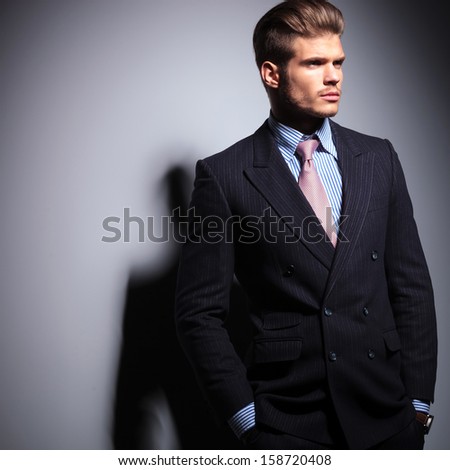 side view of a young fashion business man looking away from the camera on gray background