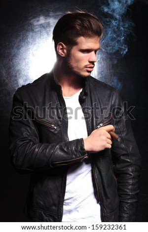 young fashion model in leather jacket smoking a big cigar and looking away from the camera