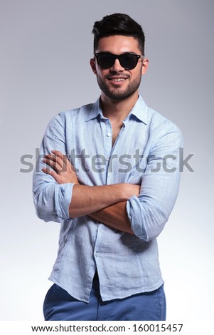 young casual man with crossed hands. on gray background
