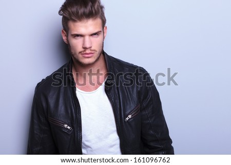 close picture of a young man with long hair in leather jacket looking at the camera