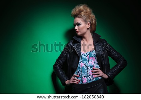side of a young sexy woman in leather jacket standing with hands on hips and looking away to her side