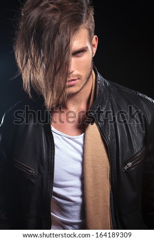 portrait of a fashion man with long hair looking at the camera on dark background