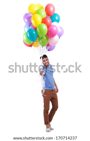 smiling casual man is offering a bunch of baloons on white background