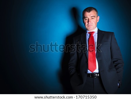 mature business man looking sad and thoughtful on blue background