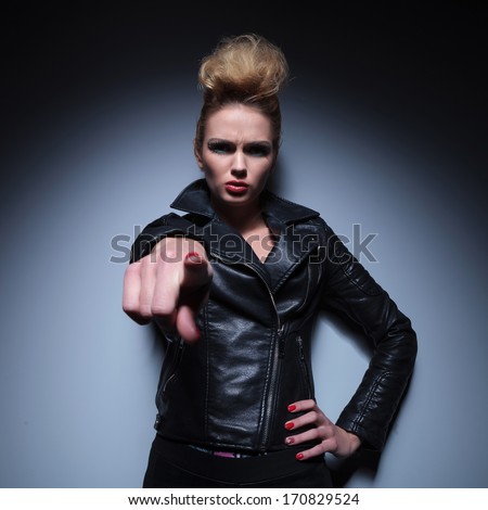 angry fashion woman in leather jacket is accusing you by pointing her finger