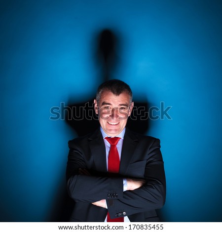 dramatic picture of a senior business man smiling on a blue background with hard shadow