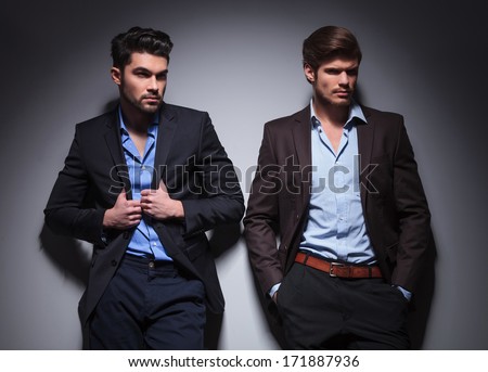 two male models looking away, one with hands in pockets, one pulling his collar