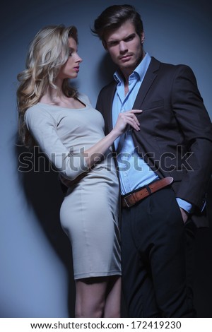 blonde woman pulling her man by his collar against studio background