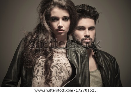 dramatic fashion couple in studio, man standing behind woman, looking at the camera