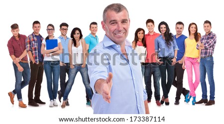 old casual man welcomes you with a handshake to his team of young people on white background