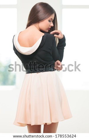 back view closeup of a young fashion woman looking at and touching her shoulder with her hand