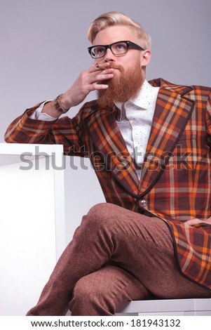 smoking young fashion man with long beard and glasses looking away from the camera