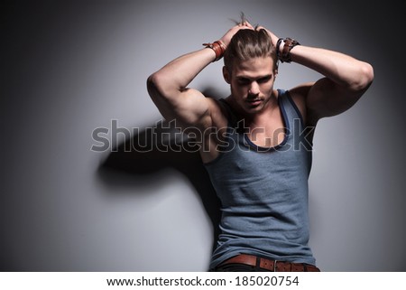 handsome young man pulling back his hair with both hands while looking into the camera. on a gray background