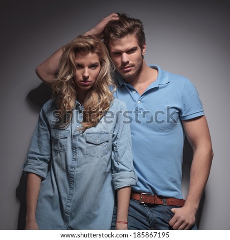 man with hand in his hair leaning against his girlfriend and posing in studio