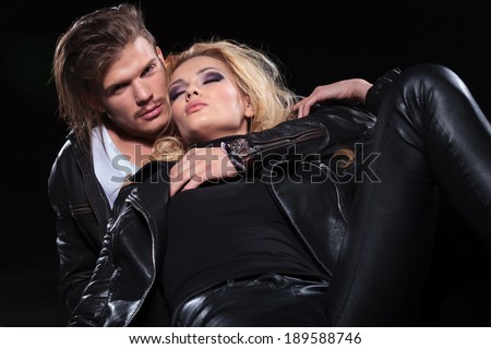 young beautiful woman sleeping on the floor, with her boyfriend supporting her while looking into the camera . on black background