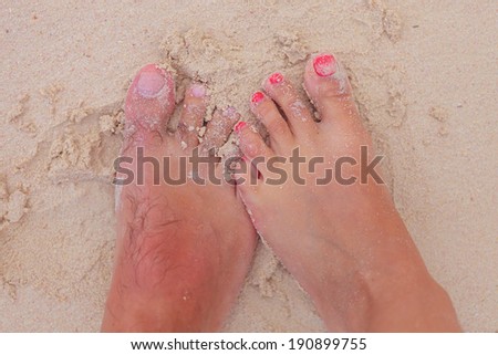 bare feet and toes of a young couple in wet sand