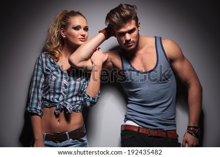 young smiling woman holding her boyfriend by his biceps, studio shot