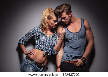 passionate couple standing against gray studio wall, in a hot pose