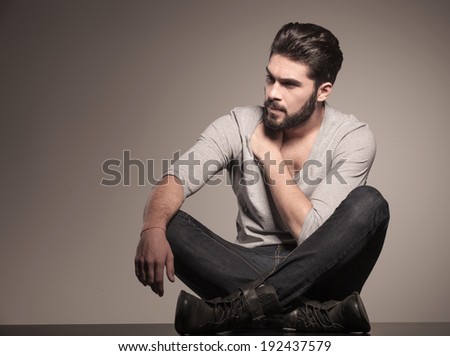 fashion man looking to his side and sits down on the floor
