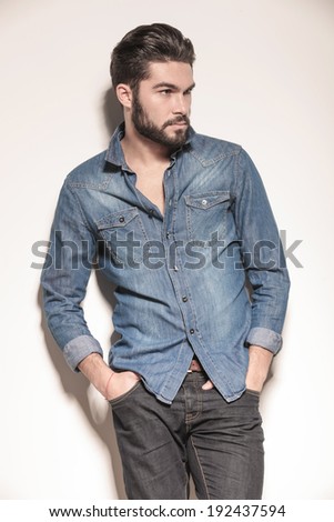 side view of a relaxed young man in jeans clothes looking away from the camera
