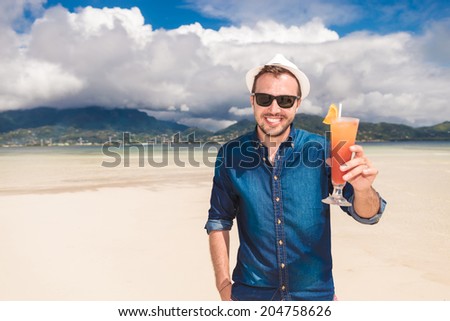 happy young man invites you to a cold drink on the beach and saying cheers!