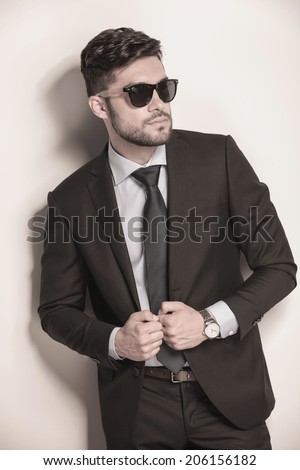 side view of a sexy business man with sunglasses holding his suit coat and looks away