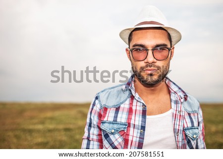 young casual man wearing hat and glasses looking at the camera