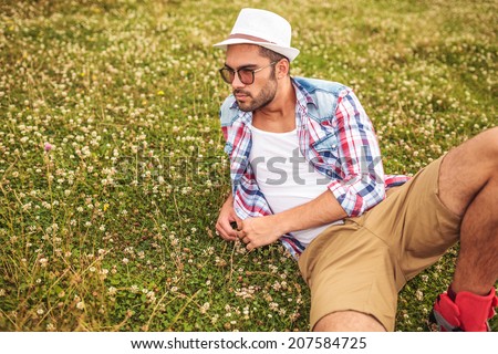side view of a man lying down on a field and thinks