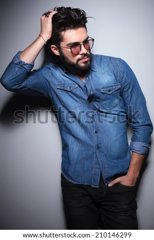 side view of a fashion man passing his hand through his hair to fix it in studio
