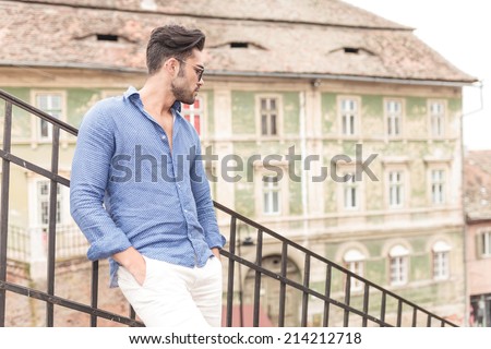 side view of a relaxed man with hands in pockets looking down the stairs