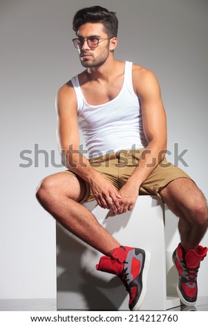 man sitting on a cube and looking to a side in studio