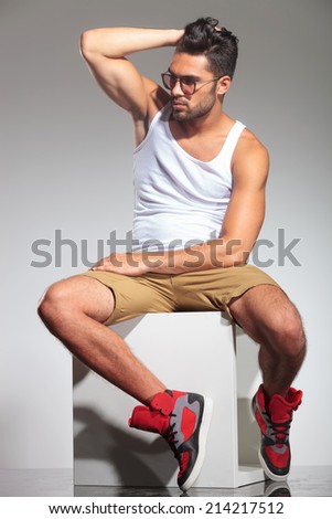 side view of a sexy fit man with hand on his head, in studio