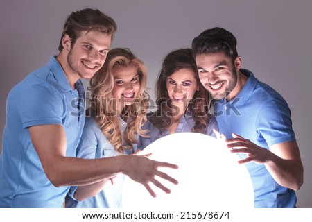 group of people with hands on big ball of light looking at the camera  grey studio background