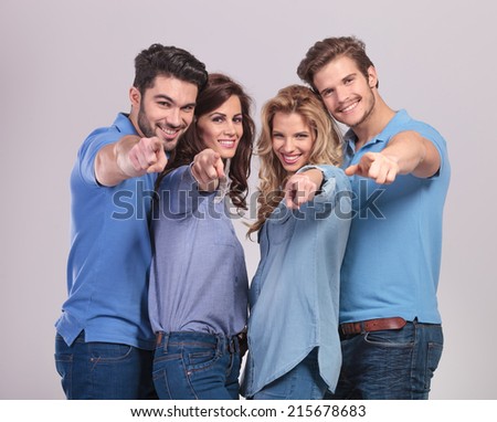 happy group of casual people pointing fingers to the camera on grey background