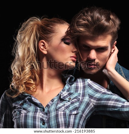 Picture of a blonde sexy woman looking away while holding her boyfriend close to her. The man is looking at the camera.