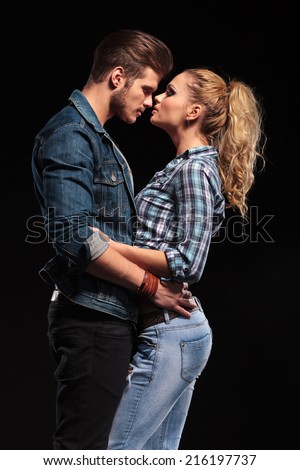 Side view of a attractive young couple holding each other, face to face, almost kissing.