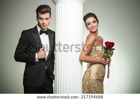 happy young married couple posing near column, woman in gown laughing