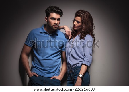 Young sexy woman leaning on her lover while looking at him. The man is holding his hands in pocket while looking away.
